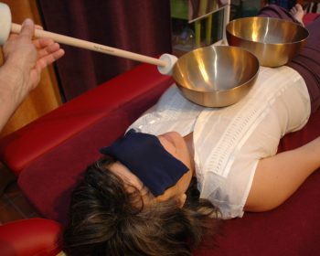 photo d'une personne recevant un massage sonore en position dorsale avec deux bols tibétains