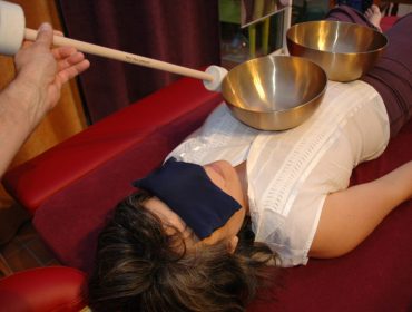 photo d'une personne recevant un massage sonore en position dorsale avec deux bols tibétains